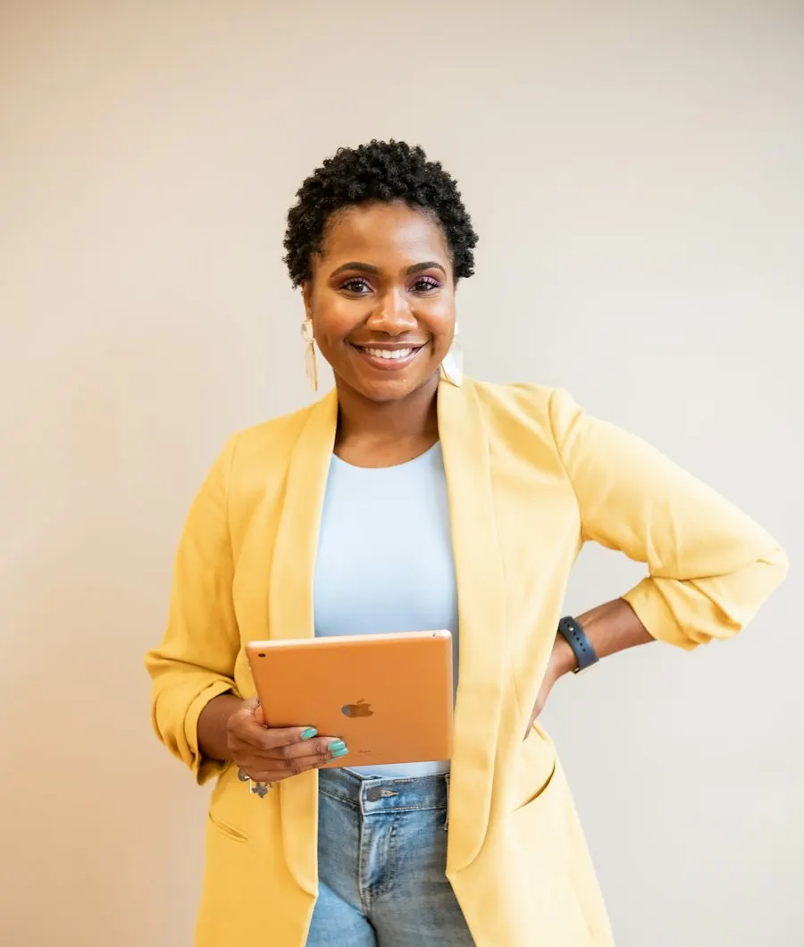 Smiling professional in a yellow blazer holding a tablet