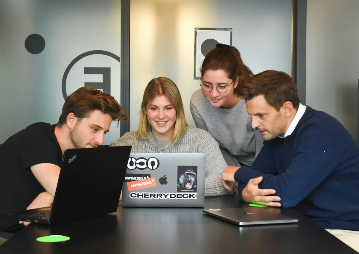 Four people collaborating around a laptop